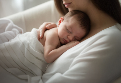 Мама держит спящего новорожденного на руках