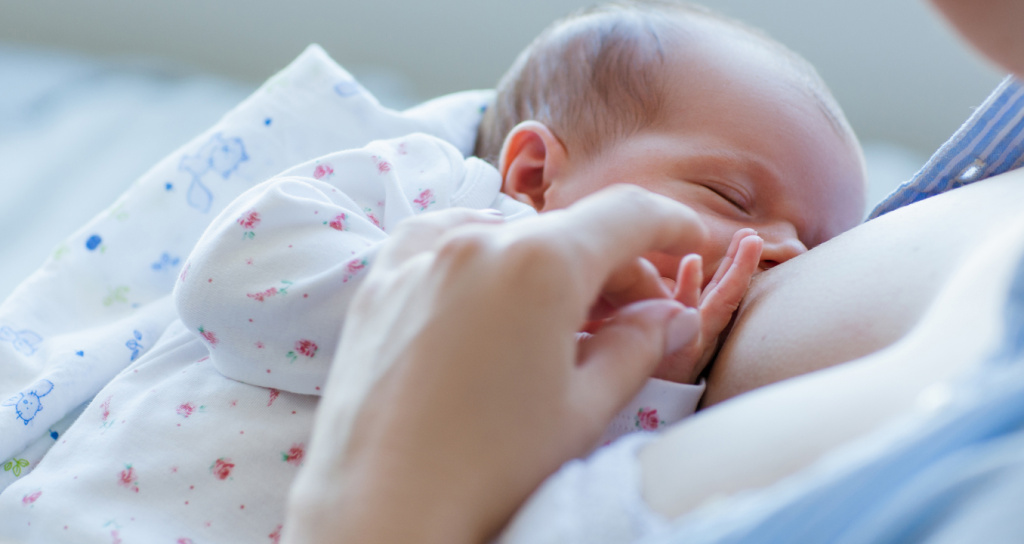 Новорождённый малыш на грудном вскармливании — грудное молоко является золотым стандартом питания