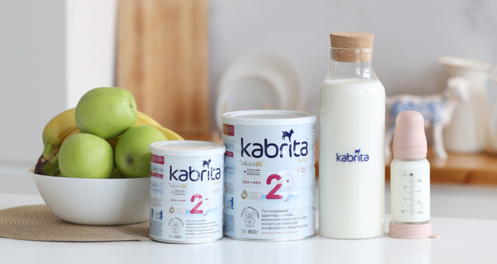 Линейка продуктов Kabrita Gold 2 — смесь, бутылочка и свежие яблоки на столе