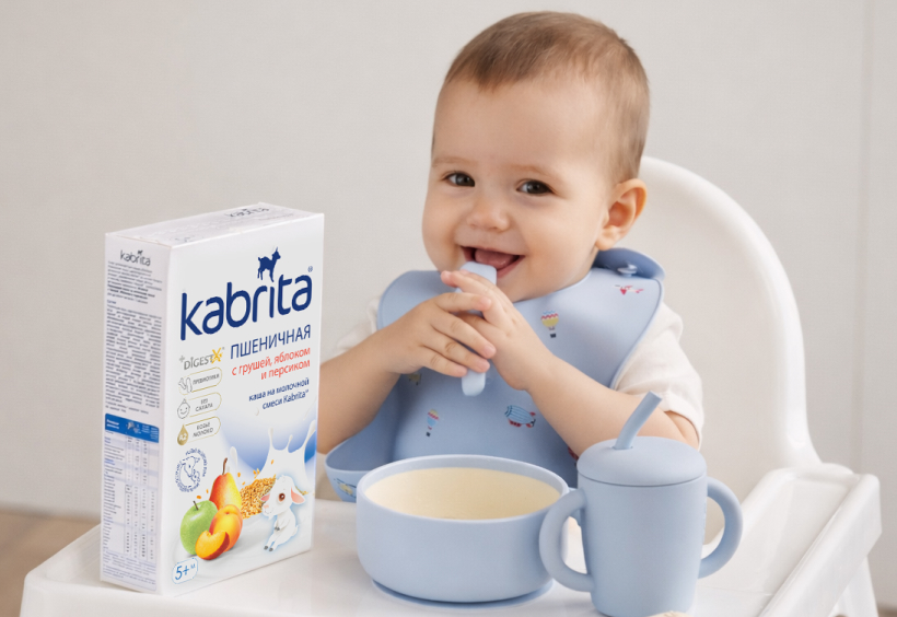 Малыш сидит за столиком рядом с кашей Kabrita