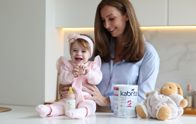 Мама готовит смесь Kabrita на кухне, рядом стоит открытая банка смеси